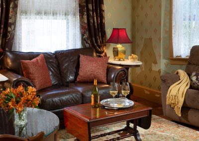 Crown Jewel Sitting Room with Leather Sofa, Reclining Chair and Wine Glasses on the Coffee Table