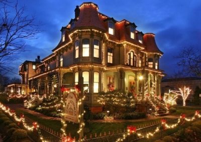 Photo taken at night of The Queen Victoria lit up with bright white Christmas lights and red bows.