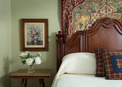 Crown Prince Guestroom Closeup of the Ornate detail of the Solid Wood King Headboard and the details of the tapestry hanging behind it.